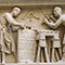 Tabernacolo dei Santi Quattro Coronati, particolare del bassorilievo raffigurante due santi al lavoro: uno edifica un muro, l'altro, che ha un trapano in mano, lavora su una colonna, Nanni di Banco, 1408, Orsanmichele, Firenze.