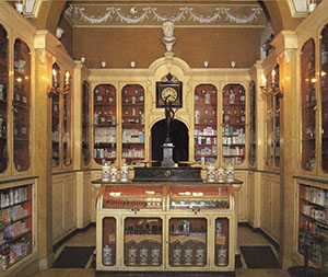 Interior of the Farmacia San Jacopo, Livorno. At center, counter scale surmounted by a bronze statuette of Mercury.