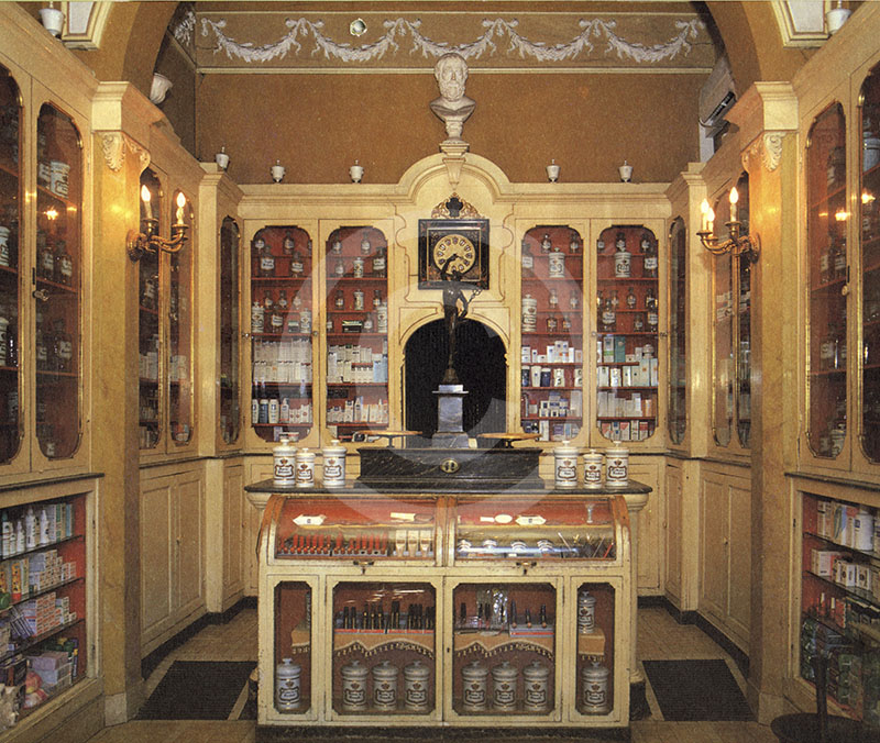 Interior of the Farmacia San Jacopo, Livorno. At center, counter scale surmounted by a bronze statuette of Mercury.