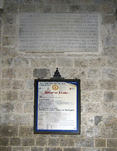 Stone tablet and advertising poster on the faade of the Accademia Musicale Chigiana, Siena.