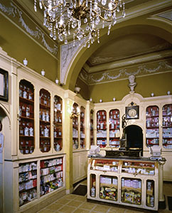 Interior of the Pharmacy of San Jacopo, Leghorn. At center, counter scale surmounted by a bronze statuette of Mercury.