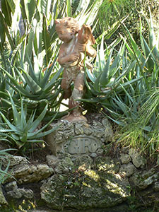 Terracotta  putto with the initials "G R" for Giorgio Roster, and aloe in the papyrus pool at the Botanical Garden of Ottonella, Portoferraio.