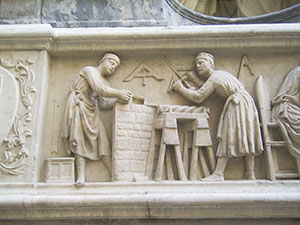 Tabernacle of the Four Crowned Saints, detail of the bas-relief depicting two saints at work:  one builds a wall, while the other holds a drill and works on a column, Nanni di Banco, 1408, Orsanmichele, Florence.